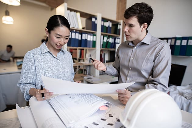 picture of male and female colleagues in discussing while looking at blueprints
