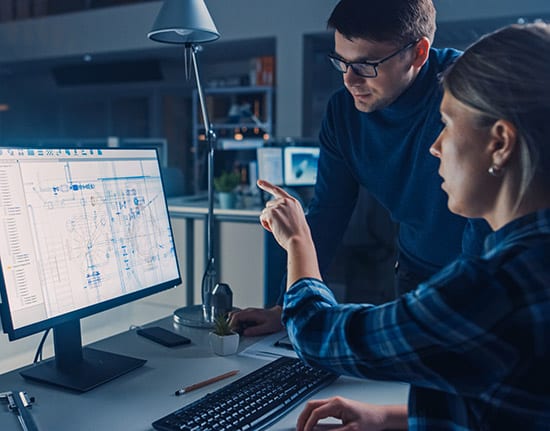 picture of woman pointing at computer screen with male colleague standing next to her